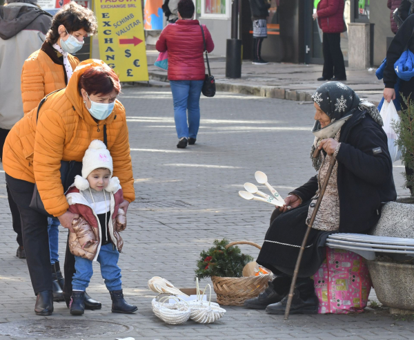 femeie impiedicandu-si copilul sa se apropie de femeia fara masca ce vindea linguri din lemn